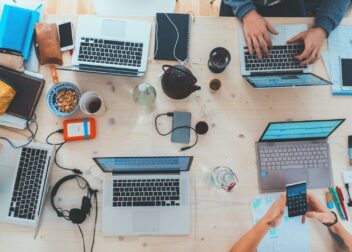 people sitting down near table with assorted laptop computers